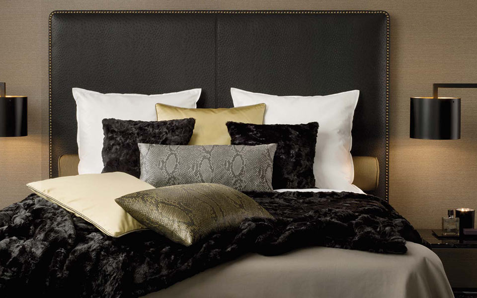 Lederbett mit hohem Kopfteil und verschiedenen Kissen