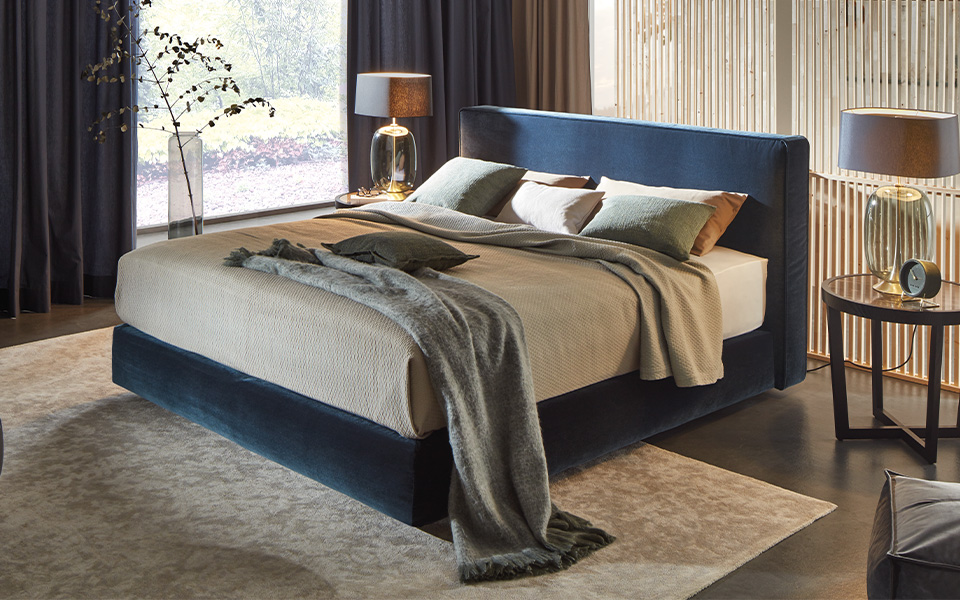 Bett mit dunkelblauem Bettgestell und grauer Bettwäsche