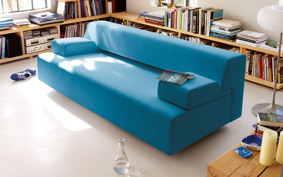 Blaue Couch inmitten eines Raumes mit Büchern